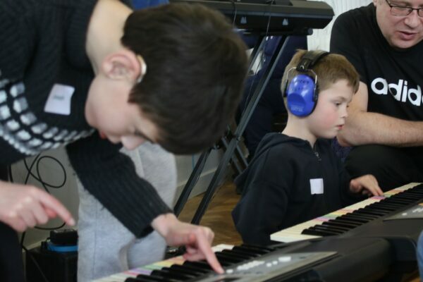 Two Boys Work Closely On A Keyboard