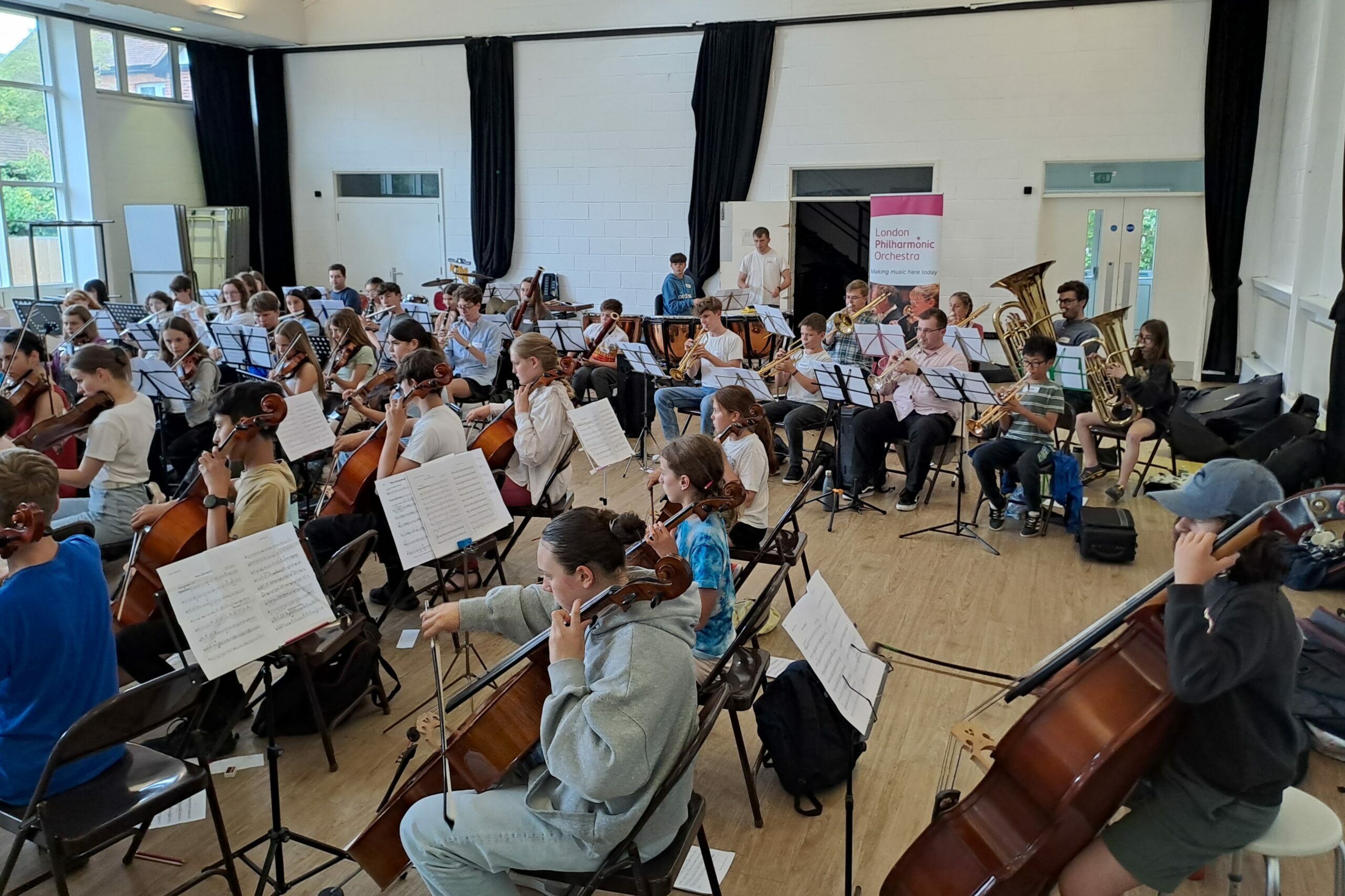Young People Sit In A Semi Circle Playing In An Orchestra