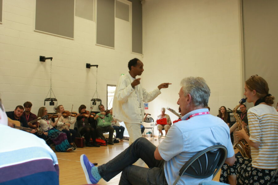 A Man Conducts Musicians Who Are Sitting Down